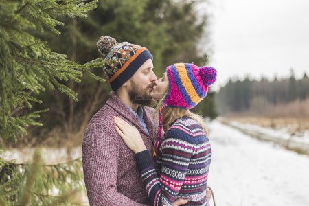 Young peaople are kissing in winter forest
