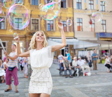 Cheerful young woman catching the soap bubbles