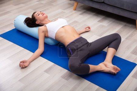 Young Woman Practicing Yoga On Bolster At Home